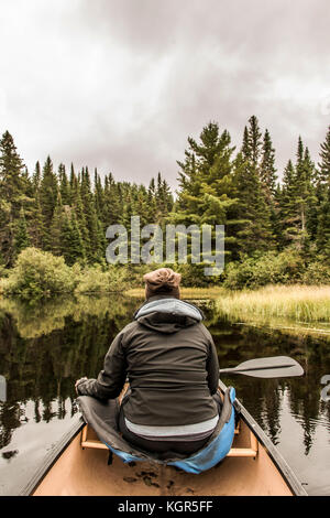 Girl canoeing with Canoe on the lake of two rivers in the algonquin national park in ontario Canada on a cloudy day Stock Photo