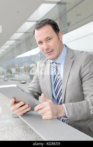 Businessman using electronic tab outside congress center Stock Photo