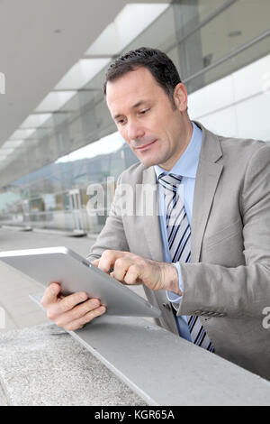 Businessman using electronic tab outside congress center Stock Photo