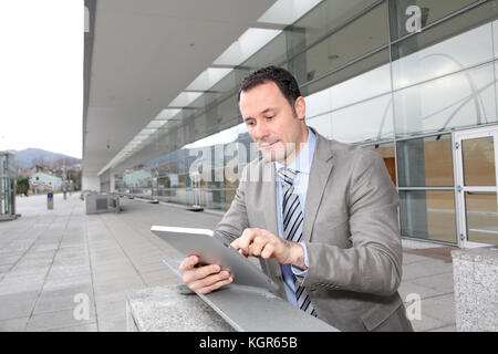 Businessman using electronic tab outside congress center Stock Photo