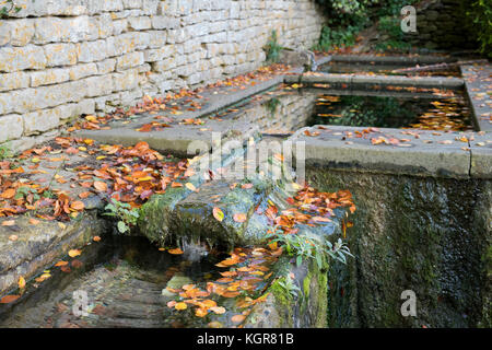 Stone water troughs covered in autumn leaves in Bisley, Cotswolds, Gloucestershire, England Stock Photo