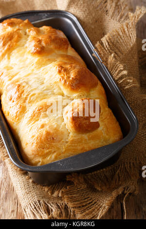 A fresh from the oven homemade rustic sausage roll cut in half on a ...