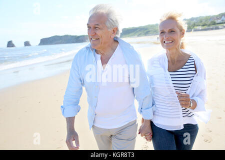 Senior couple running on a sandy beach Stock Photo