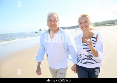 Senior couple running on a sandy beach Stock Photo