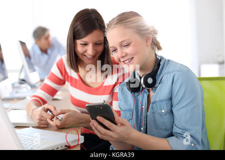 Girlfriends in class using smartphone Stock Photo