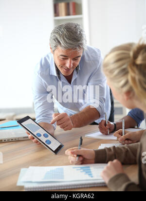 Teacher in classroom using tablet with students Stock Photo