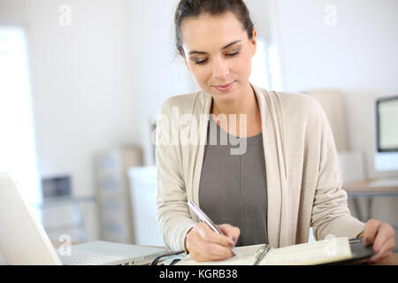 Businesswoman writing on agenda in office Stock Photo