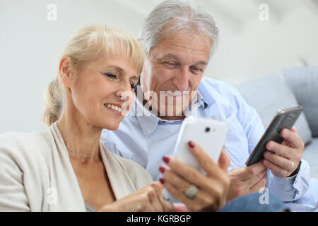 Senior couple at home using smartphone Stock Photo