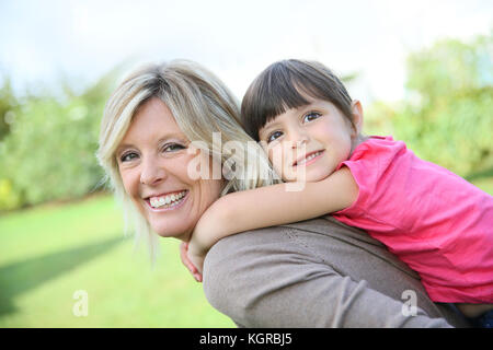 Mother giving piggyback ride to little girl
