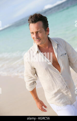 Handsome 40-year-old man walking on beach Stock Photo