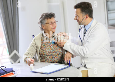 Doctor examining elderly woman in nursing home Stock Photo
