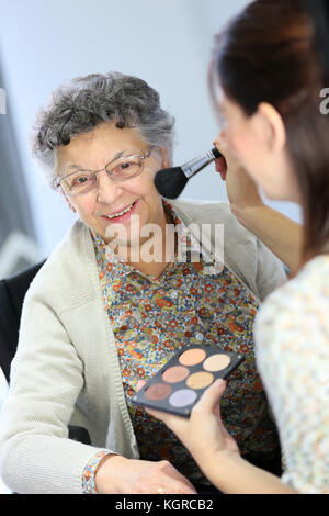 Home carer helping elderly woman to put makeup on Stock Photo