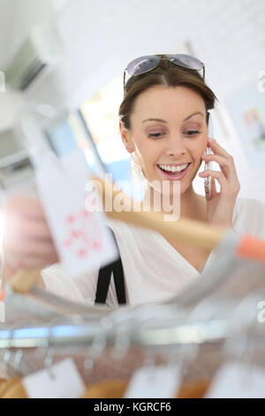 Woman in clothing store talking to friend on phone Stock Photo