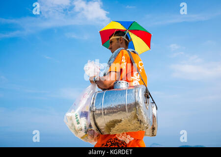 RIO DE JANEIRO - MARCH 30, 2016: Brazilian beach vendor selling South American mate tea walks in uniform with a sun shade hat along Ipanema Beach. Stock Photo