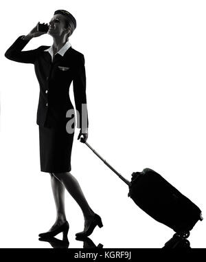 one caucasian Stewardess cabin crew  woman walking on the phone isolated on white background in  silhouette Stock Photo