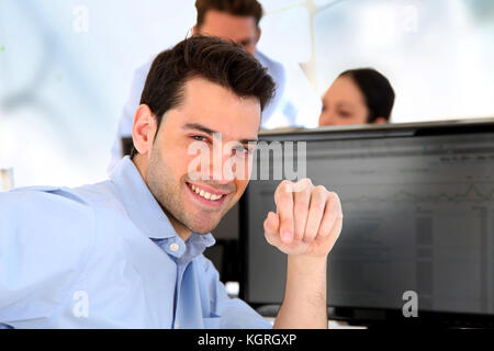 Smiling trader in front of desktop computer Stock Photo