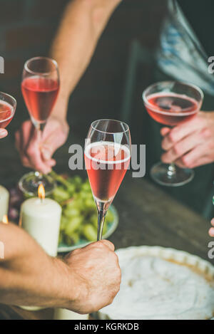Holiday celebration table setting with food. Friends hands eating and drinking together. People having party, gathering, celebrating with rose champai Stock Photo