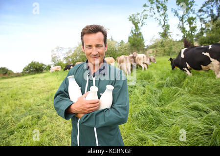 Farmer in field holding bottles of milk Stock Photo