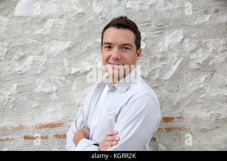 Smiling handsome man leaning on wall Stock Photo