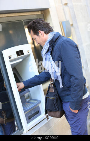 Man withdrawing money from ATM machine Stock Photo