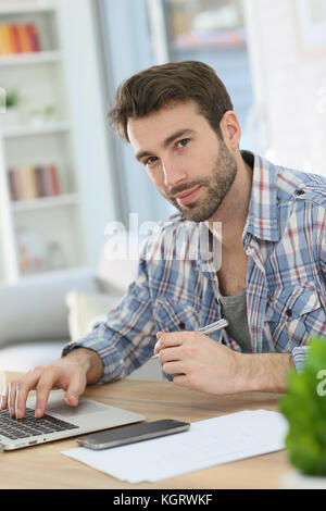 Man working from home with laptop and taking notes Stock Photo