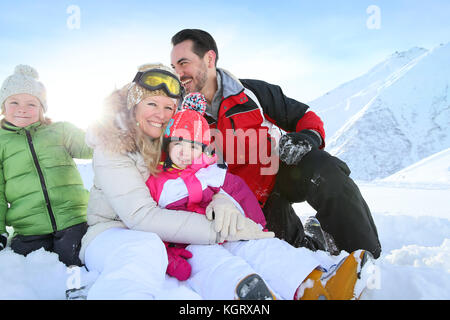 Cheerful family sitting in snow Stock Photo