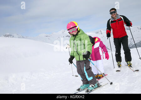 Family skiing down ski slope in winter Stock Photo