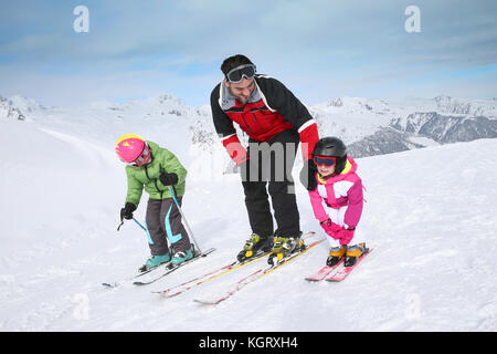 Ski instructor teaching young kids to go down ski slope Stock Photo