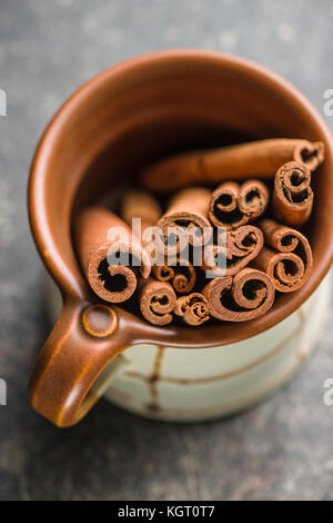 Cinnamon sticks in cup on old table. Stock Photo