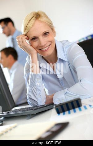 Cheerful businesswoman sitting in front of desktop Stock Photo