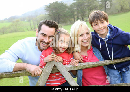 Family leaning on a fence in countryside Stock Photo