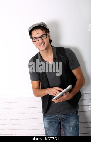 Trendy guy using electronic tablet leaning on wall Stock Photo