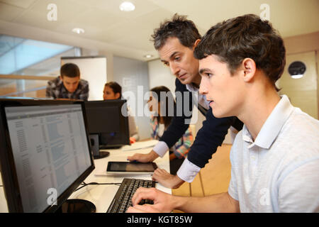 Adult man helping student in classroom Stock Photo