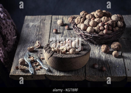 Various nuts with with old nutcracker on wooden table Stock Photo