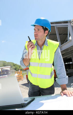 Foreman using walkie-talkie on construction site Stock Photo