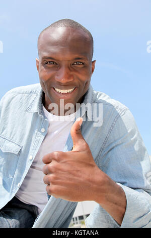Man showing thumbs up with blue sky Stock Photo