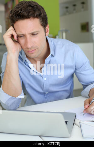 Man with doubtful look in front of laptop Stock Photo