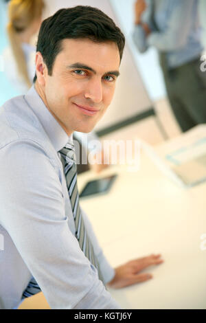 Confident businessman leaning on table Stock Photo
