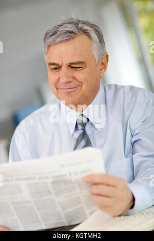 Portrait of senior businessman reading newspaper Stock Photo
