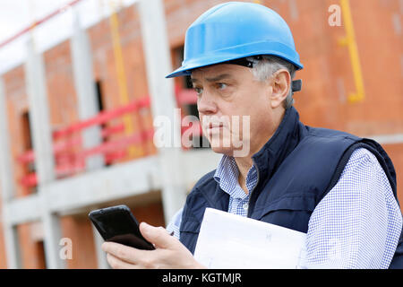 Entrepreneur on construction site using smartphone Stock Photo
