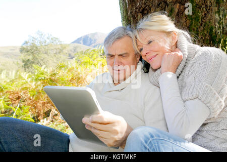 Senior couple using tablet in forest Stock Photo
