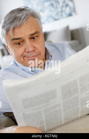 Senior man reading newspaper with puzzled look Stock Photo