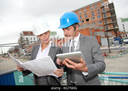 Construction engineers checking plan on building site Stock Photo