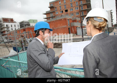 Construction engineers checking plans on building site Stock Photo
