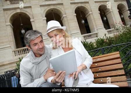 Trendy couple using electronic tablet on city bench Stock Photo