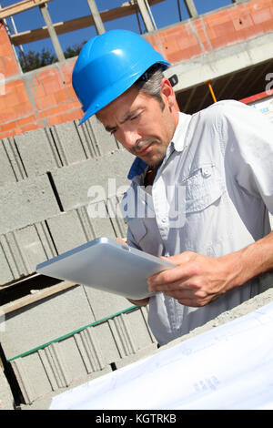 Construction manager using electronic tablet on building site Stock Photo