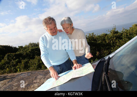 Senior couple looking at road map on car hood Stock Photo