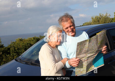 Senior couple looking at road map on car hood Stock Photo