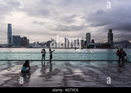 HONG KONG, CHINA - JUNE 16, 2017: Two young Asian women take a selphie with their smartphone in front of the Kowloon skyline in Hong Kong Stock Photo