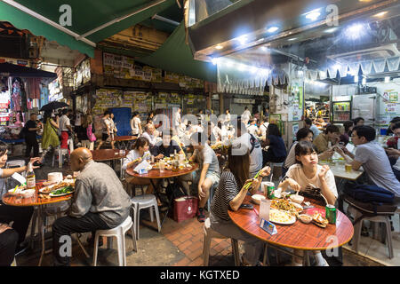 HONG KONG, CHINA - JUNE 16, 2017: Tourists and local dine in a restaurant in the streets of Kowloon near the famous Temple night market in Hong Kong. Stock Photo